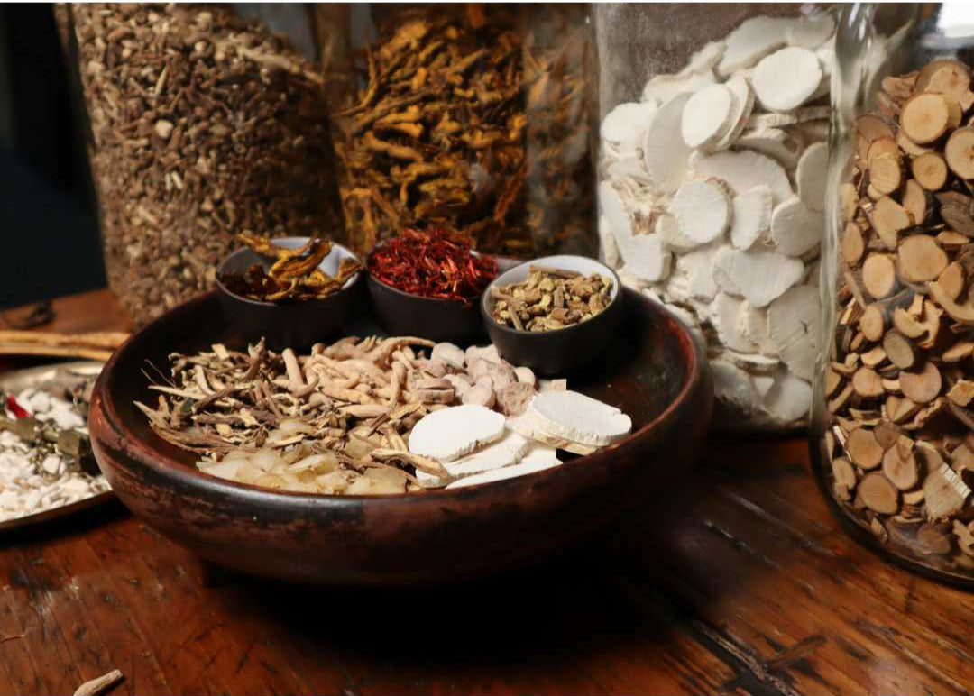 Assorted dried herbs and spices in bowls on a wooden surface